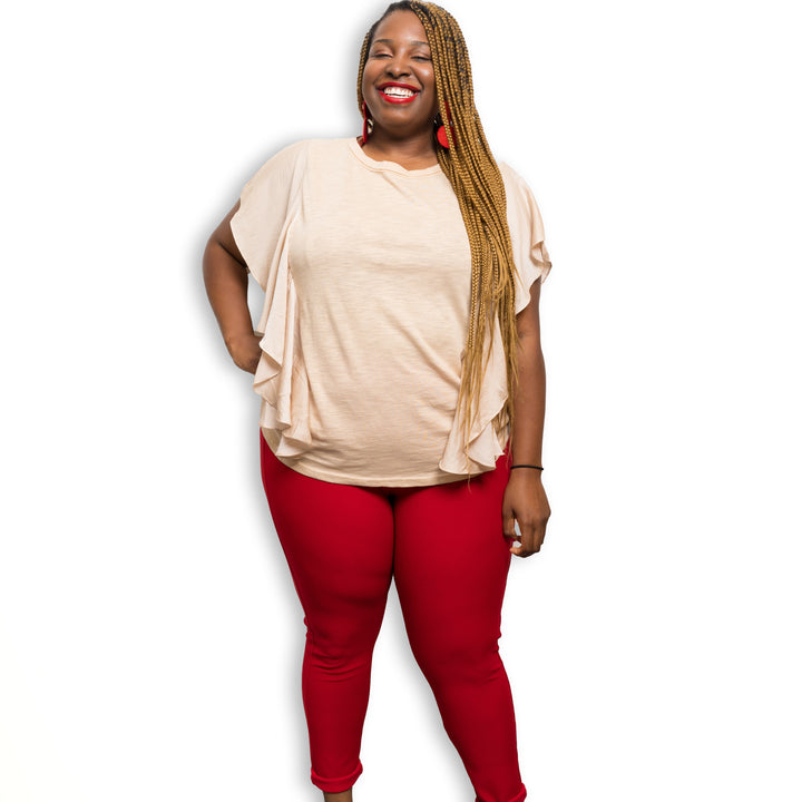 red scuba high waist pull on pants paired with a beige ruffle top and red earrings on a plus sized model and white background